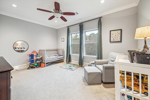 carpeted bedroom featuring a crib, baseboards, ceiling fan, crown molding, and recessed lighting