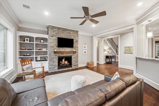 living area with a fireplace, wood finished floors, visible vents, stairs, and ornamental molding