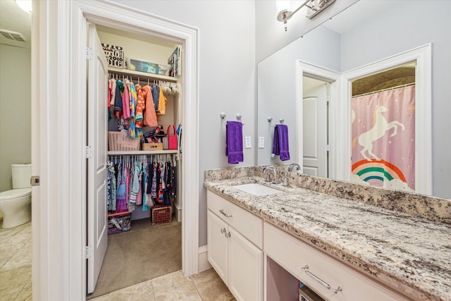 bathroom featuring toilet, a spacious closet, vanity, and visible vents