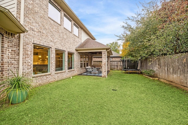 view of yard featuring a trampoline, a patio area, and a fenced backyard