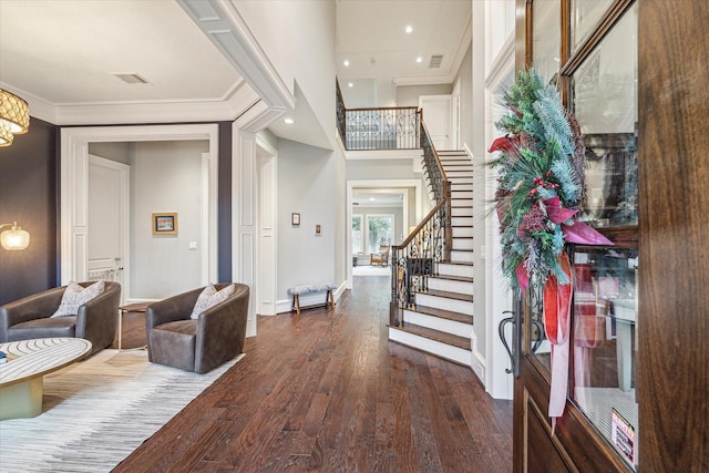 foyer entrance featuring visible vents, stairway, dark wood-type flooring, ornamental molding, and baseboards