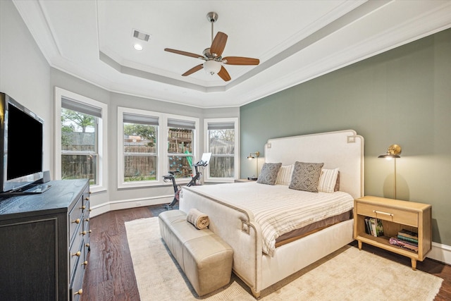 bedroom featuring dark wood finished floors, a raised ceiling, visible vents, ornamental molding, and baseboards