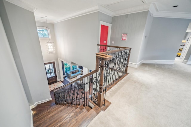 stairway featuring carpet floors, baseboards, a chandelier, and crown molding