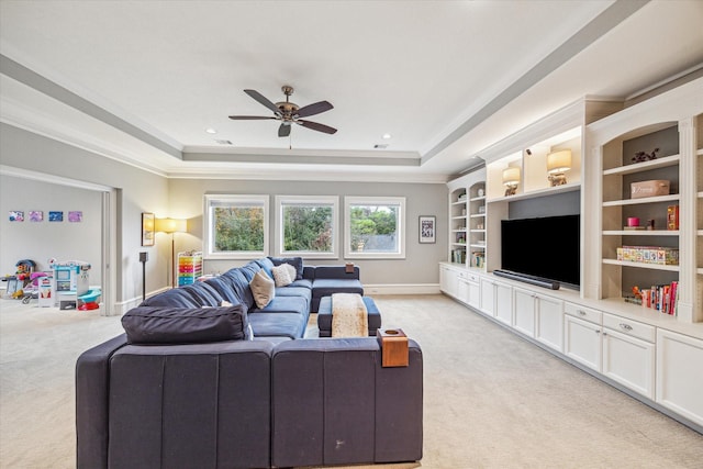 living room featuring baseboards, a tray ceiling, a ceiling fan, and light colored carpet