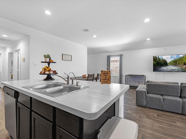 kitchen with dark wood-type flooring, a sink, visible vents, stainless steel dishwasher, and an island with sink