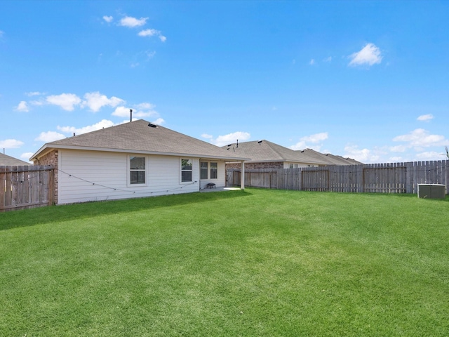 rear view of property featuring a yard and a fenced backyard