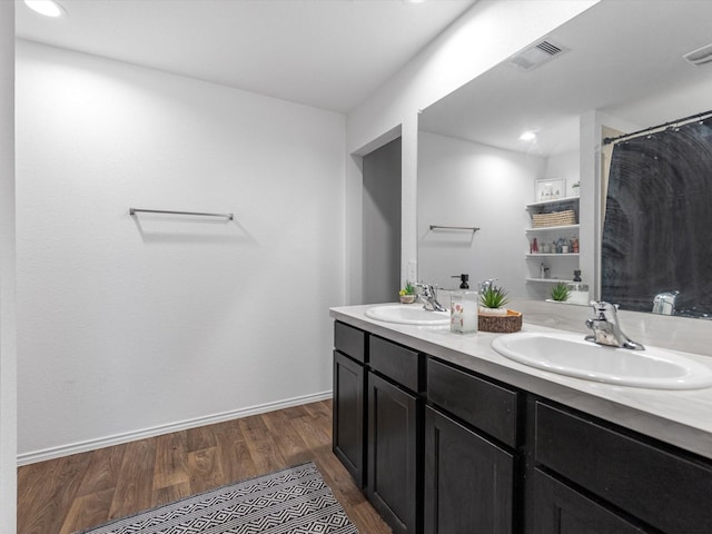 bathroom with double vanity, wood finished floors, a sink, and visible vents