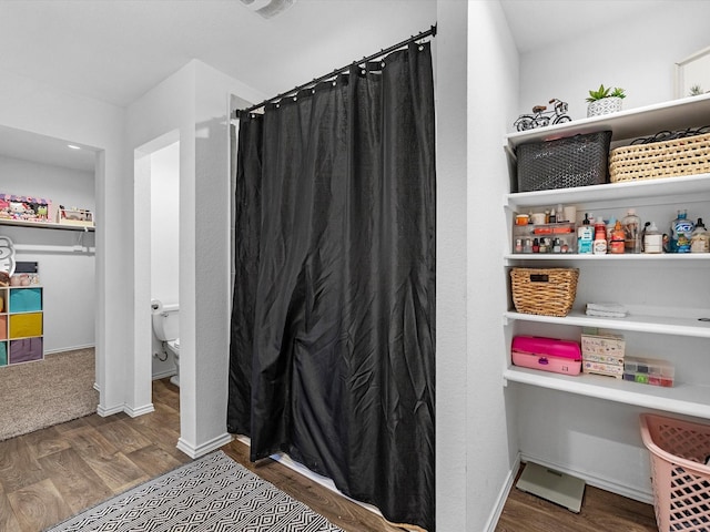 full bathroom featuring toilet, curtained shower, baseboards, and wood finished floors