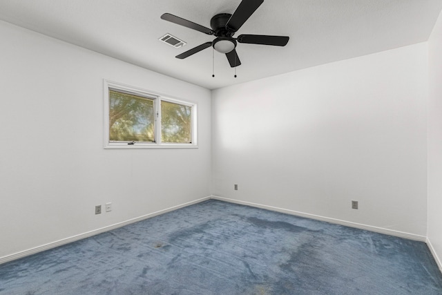 spare room with ceiling fan, baseboards, visible vents, and dark carpet