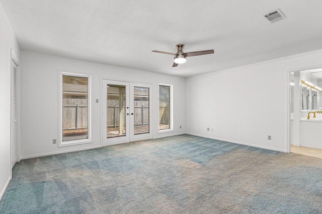 carpeted spare room featuring french doors, visible vents, a ceiling fan, a textured ceiling, and baseboards