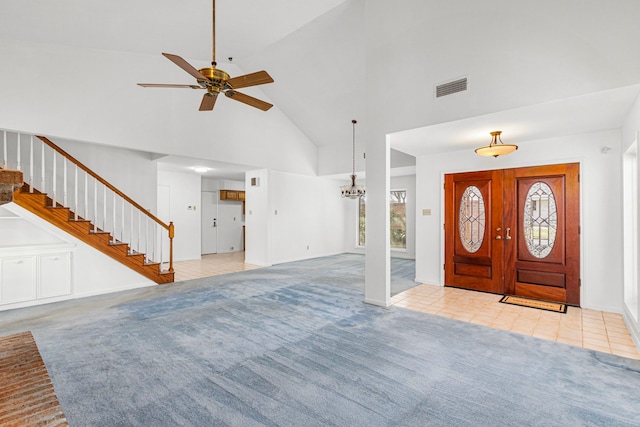 carpeted entryway featuring high vaulted ceiling, tile patterned flooring, ceiling fan with notable chandelier, visible vents, and stairs