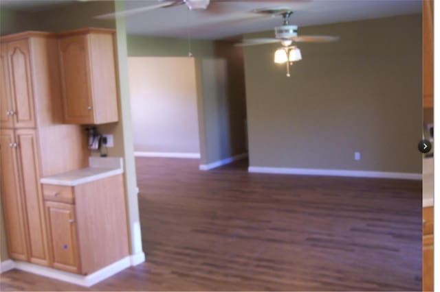 kitchen with dark wood-type flooring, baseboards, light countertops, and a ceiling fan