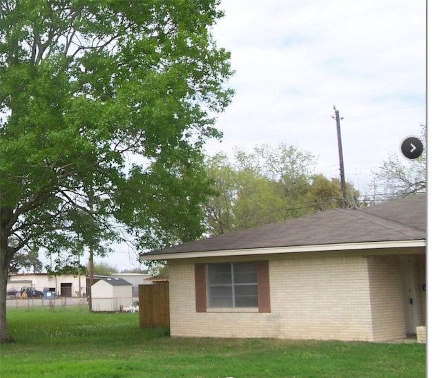 view of side of property featuring a yard, brick siding, and fence