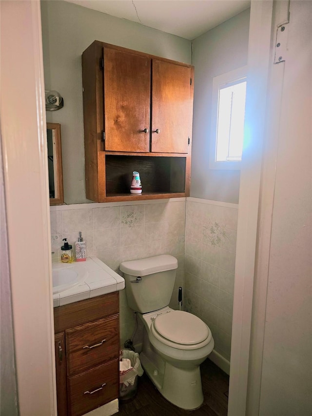 half bathroom featuring tile walls, vanity, and toilet