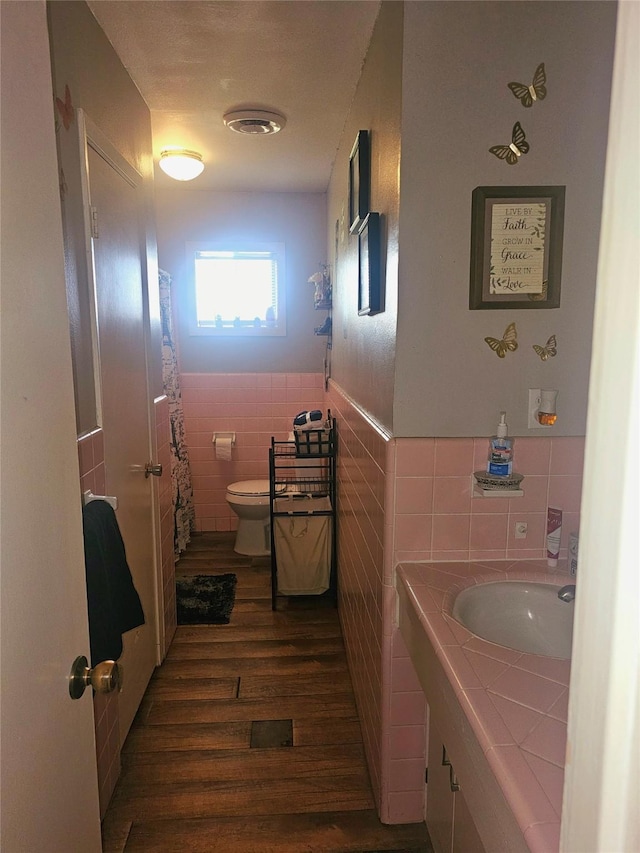 full bathroom with wood finished floors, vanity, tile walls, a wainscoted wall, and toilet