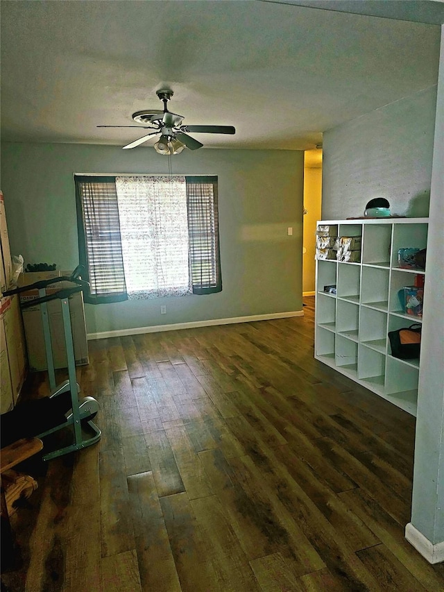unfurnished living room featuring hardwood / wood-style flooring, baseboards, and a ceiling fan