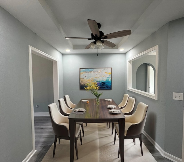 dining space featuring a tray ceiling, wood finished floors, a ceiling fan, and baseboards