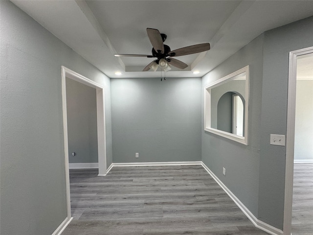 spare room featuring baseboards, a raised ceiling, and wood finished floors