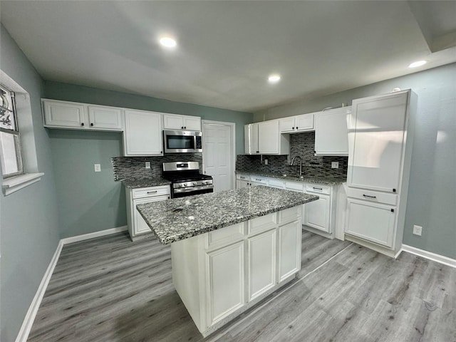 kitchen with light wood-style flooring, appliances with stainless steel finishes, white cabinets, and a sink