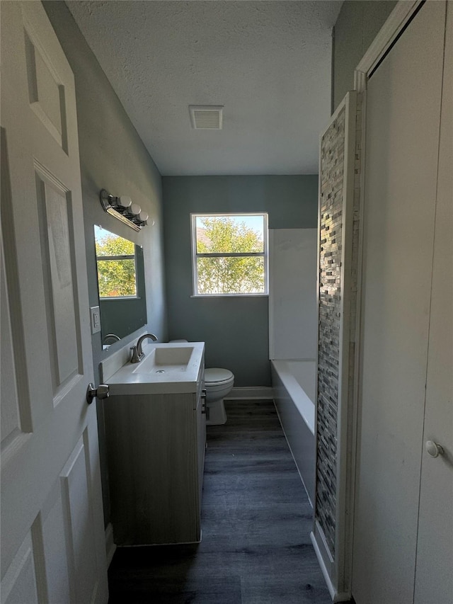 bathroom featuring visible vents, toilet, wood finished floors, a textured ceiling, and vanity