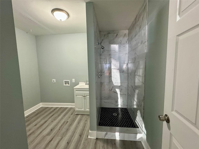 bathroom featuring baseboards, vanity, a marble finish shower, and wood finished floors