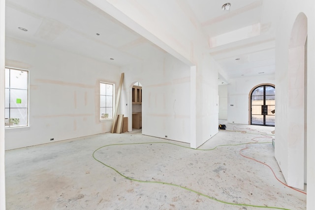 spare room featuring a healthy amount of sunlight and arched walkways