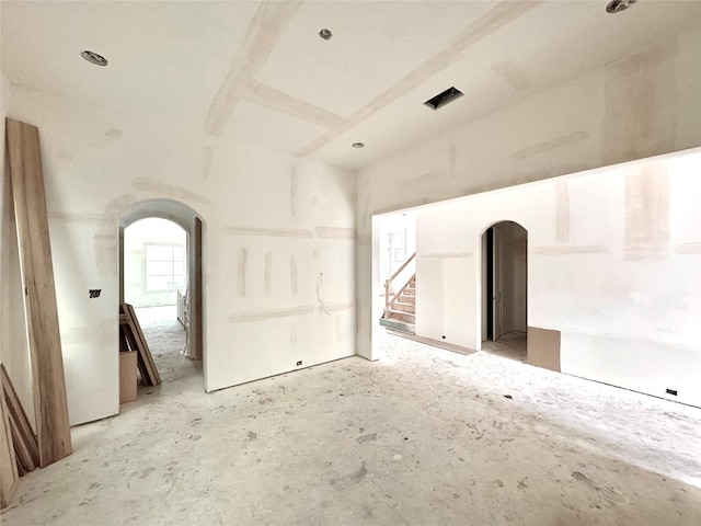 unfurnished room with arched walkways and stairs