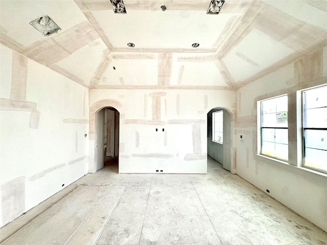 empty room featuring arched walkways and high vaulted ceiling