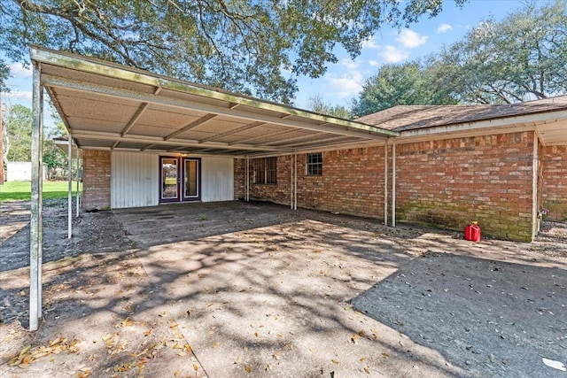 rear view of property with a carport, aphalt driveway, and brick siding