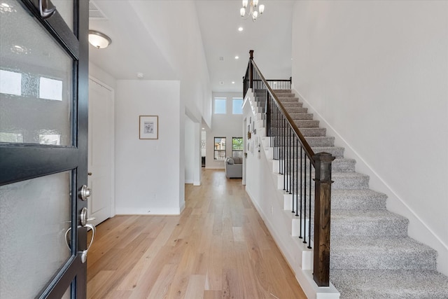 entryway with an inviting chandelier, stairs, a high ceiling, light wood-style floors, and recessed lighting