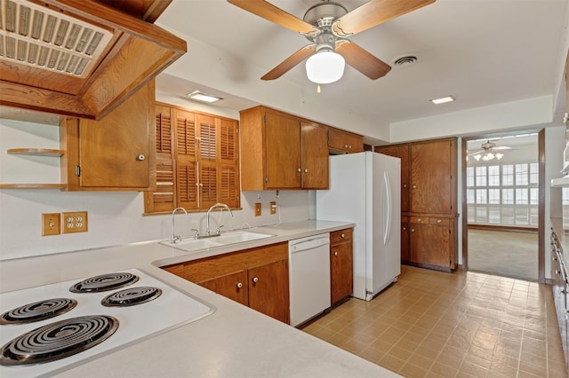 kitchen featuring a sink, white appliances, brown cabinetry, and light countertops