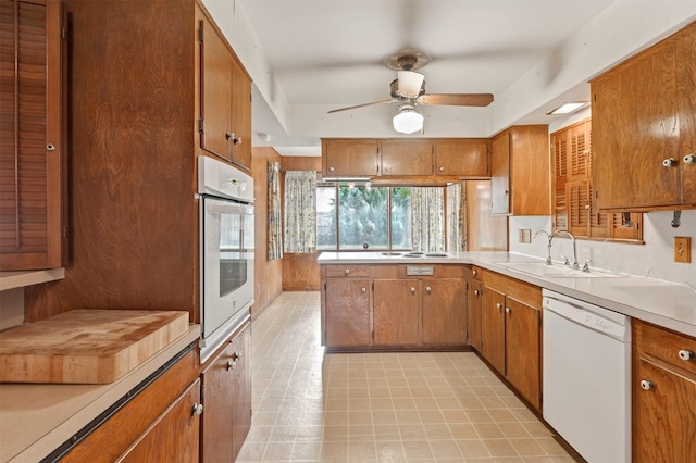 kitchen featuring brown cabinets, white appliances, and a sink