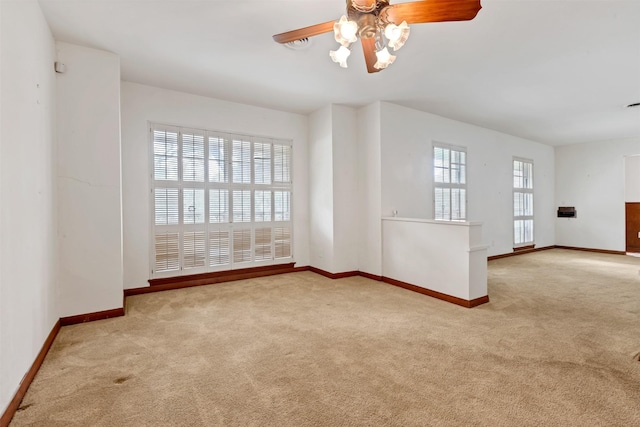 carpeted empty room featuring visible vents, a ceiling fan, and baseboards