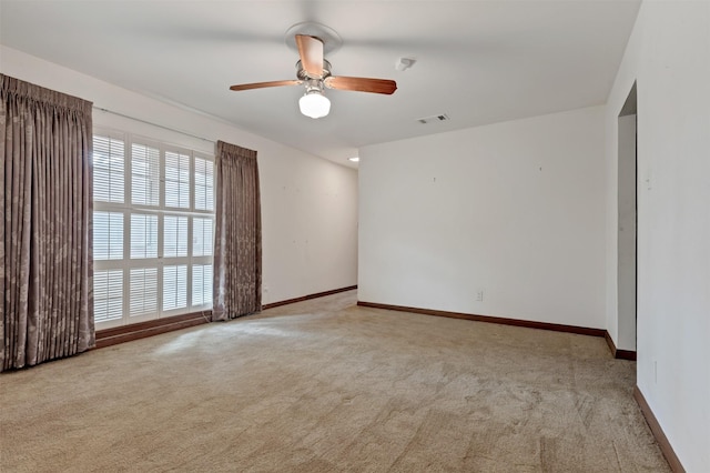 carpeted empty room with visible vents, baseboards, and a ceiling fan