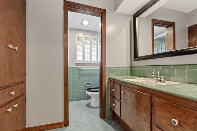 bathroom with a wainscoted wall, toilet, tile walls, and vanity