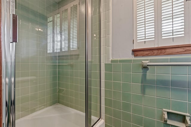 bathroom with tiled shower, tile walls, and wainscoting