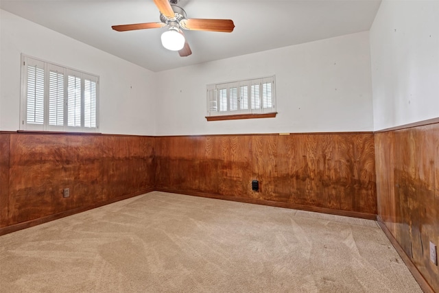 unfurnished room with a wainscoted wall, carpet, and wooden walls