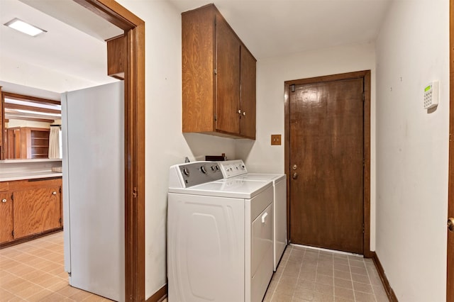 washroom with baseboards, cabinet space, and washing machine and clothes dryer