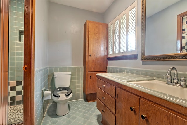 bathroom featuring tile patterned floors, a wainscoted wall, toilet, tile walls, and vanity