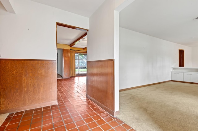 interior space featuring a wainscoted wall, wood walls, carpet flooring, and tile patterned flooring