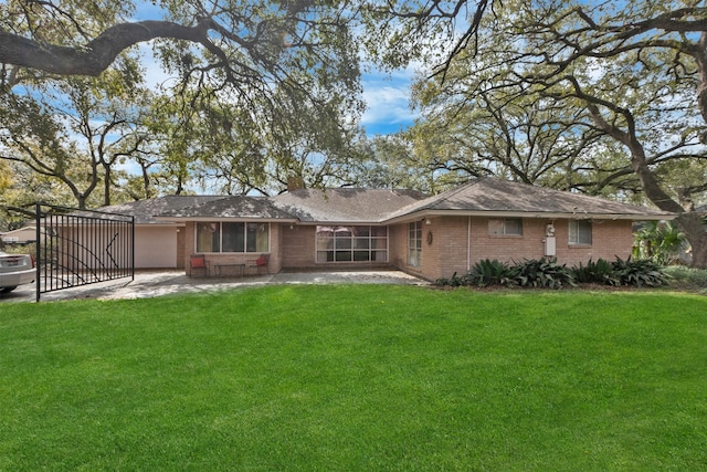 rear view of house featuring a patio area, a yard, brick siding, and a garage