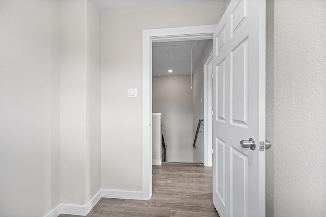 corridor with attic access, wood finished floors, an upstairs landing, and baseboards