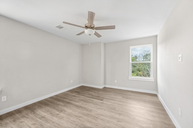 empty room featuring a ceiling fan, light wood-type flooring, visible vents, and baseboards