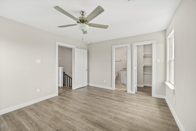 unfurnished bedroom with a walk in closet, light wood-style flooring, and baseboards