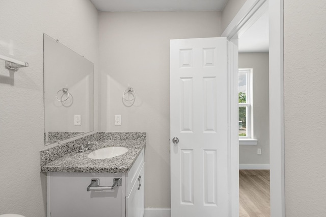 half bathroom with vanity, baseboards, and wood finished floors