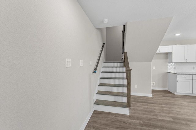 staircase with recessed lighting, baseboards, and wood finished floors