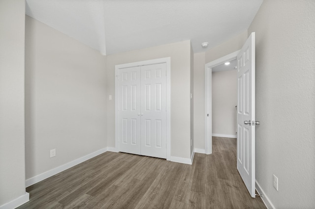 unfurnished bedroom featuring a closet, wood finished floors, and baseboards