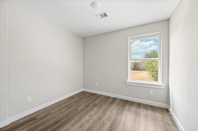 unfurnished room featuring baseboards, visible vents, and wood finished floors