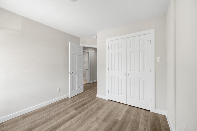 unfurnished bedroom featuring a closet, baseboards, and wood finished floors