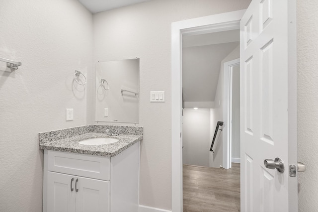 bathroom with a textured wall, wood finished floors, and vanity